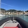 View from the bow of a rubber boat approaching a harbor with sailboats and buildings on a hillside
